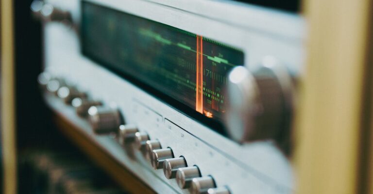 Um rádio vintage com mostrador iluminado e botões metálicos.